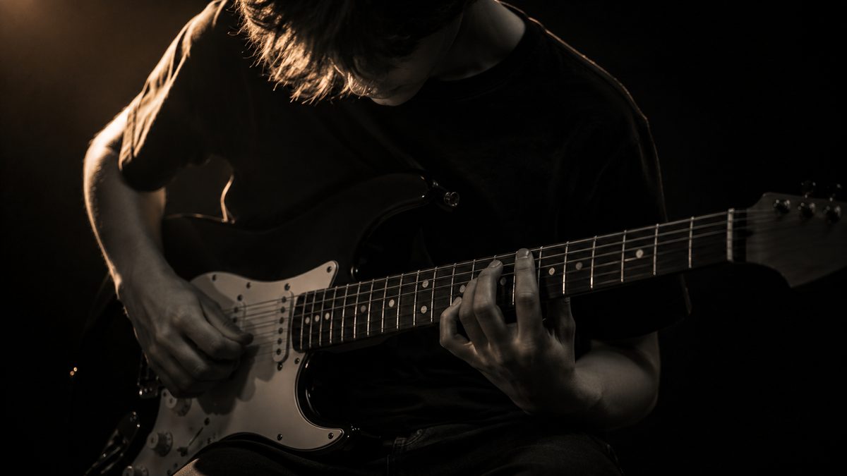 Adolescente aprendendo a tocar guitarra